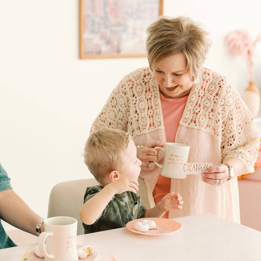 A grandma holds her GRANDMA sticker while smiling at her grandson.