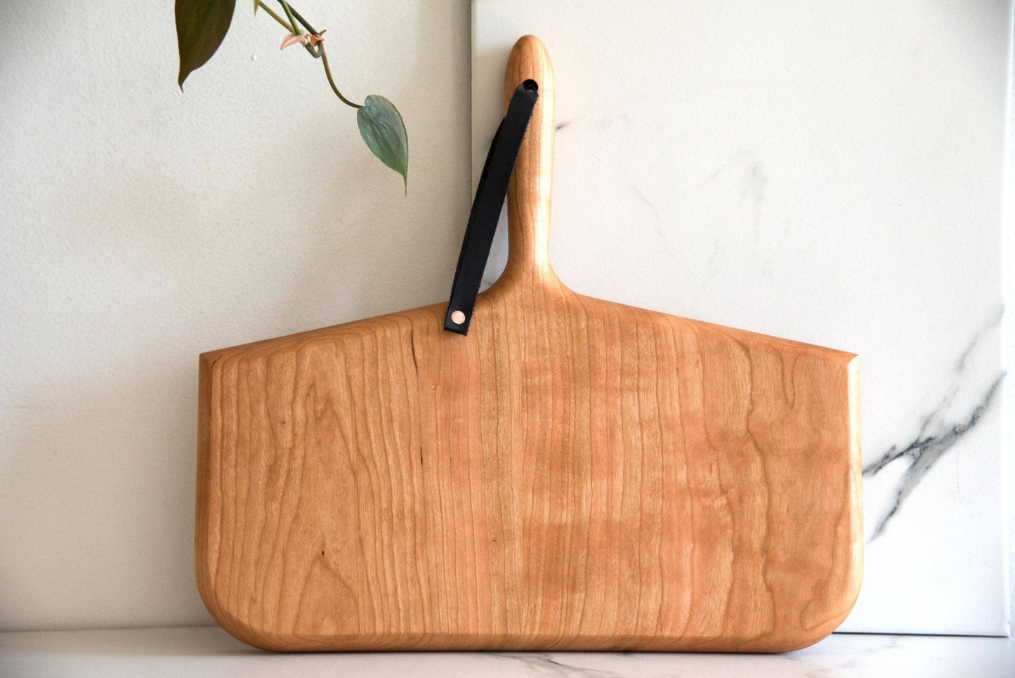 The whale bone cutting board, made of cherry wood, looks beautiful resting on your countertop.