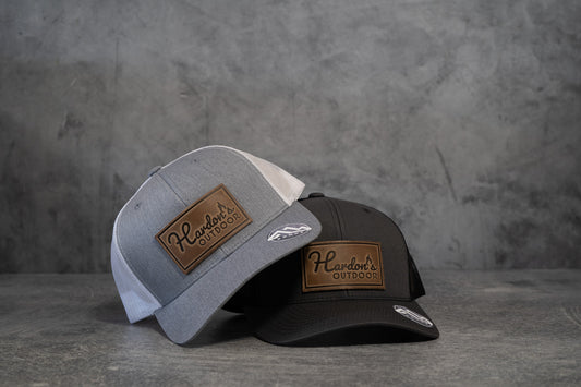 Buy 1 (one) Hardon's Outdoor hat with leather logo in choice of two color combos—heather gray and white, or dark charcoal gray and black. 