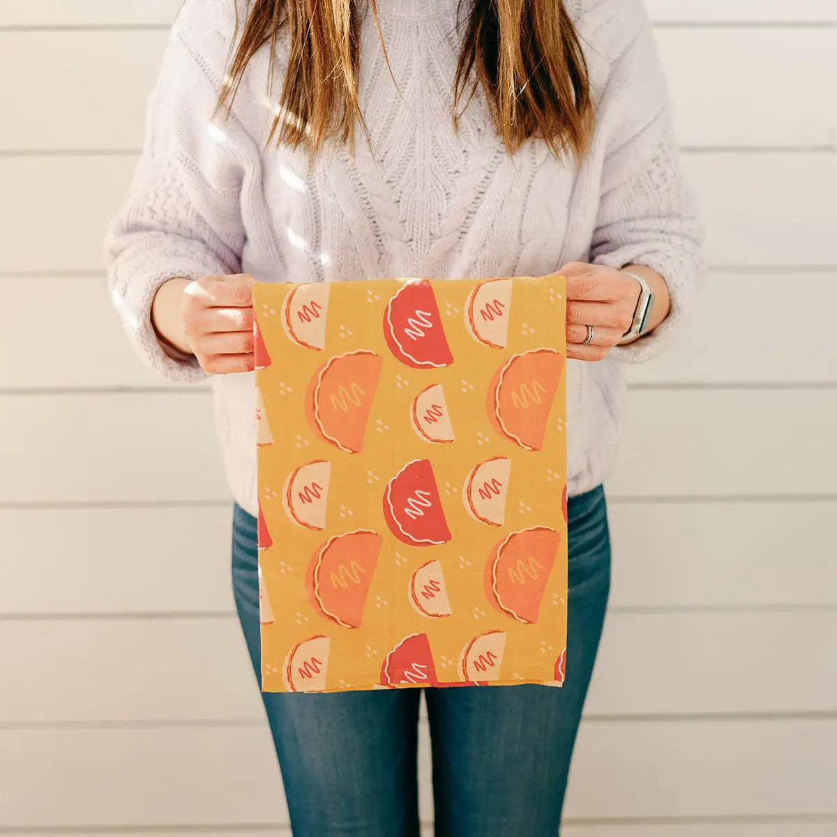 A woman holds a Taco Tuesday towel she purchased. 