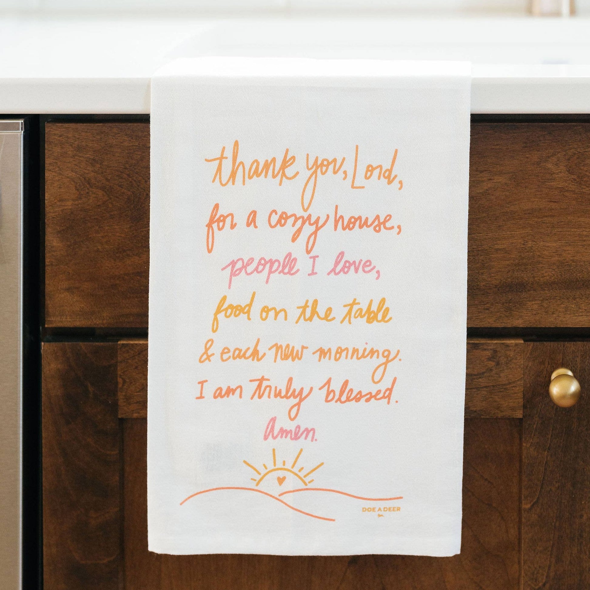 This tea towel design has shades of orange, pink and yellow on a white towel. 