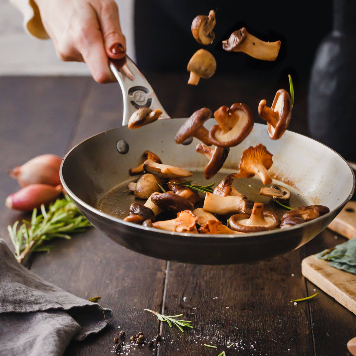 A woman tosses mushrooms as they brown in the MINERAL B Pro pan.