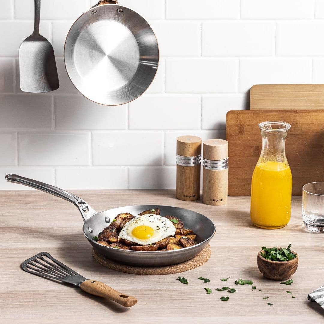 Fried breakfast potatoes and a sunny-side-up egg are served in a MINERAL B Pro skillet. 