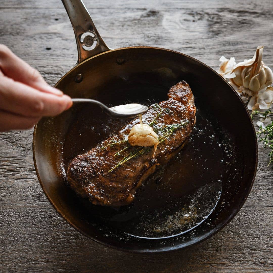 A steak with a deep crust is basted with butter and garlic in a MINERAL B skillet. 