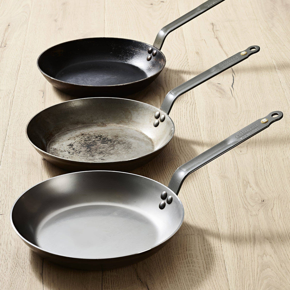 Three pans demonstrate the patina process, each one growing darker and more non-stick with each use. 